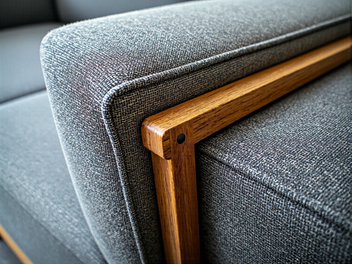 Szary tapicerowany fotel z drewnianym podłokietnikiem dębowym